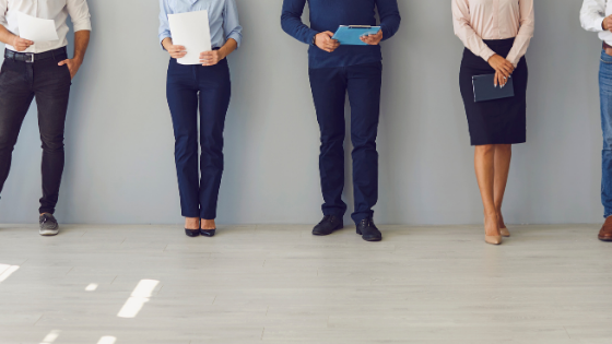 Image shows the feet of professionals standing against a wall